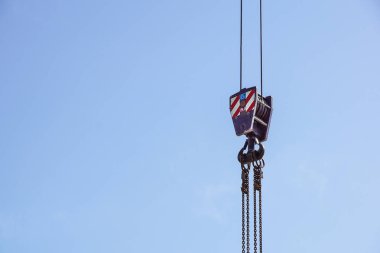 Kırmızı ve beyaz çizgili turna kancası asılı, mavi gökyüzü arka planda .