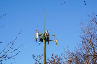 Çelik telekomünikasyon kule mavi gökyüzü ve ağaçlar üzerinde antenler ile