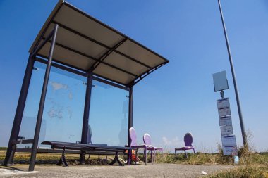 Tarlaların yanında kırsal bir otobüs durağı ve eski sandalye hasarı