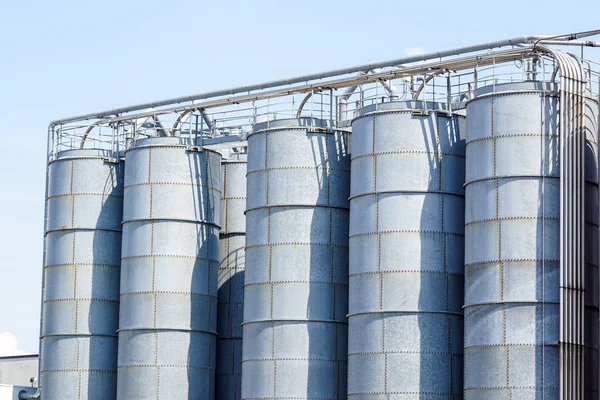 Silos agricoli. Edificio Esterno. Stoccaggio ed essiccazione di cereali, frumento, mais, soia, girasole contro il cielo blu con nuvole bianche — Foto Stock