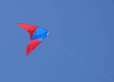 masmavi bir gökyüzü güneş ışığı ile kırmızı yay sallayarak ile renkli bir uçurtma görüş açısı