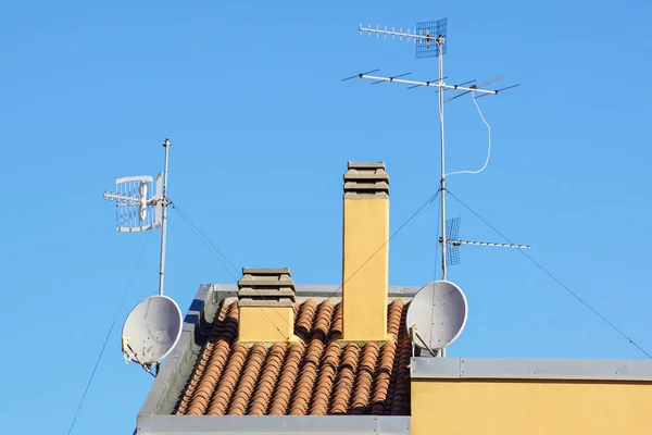 Antenne satellite et vieille antenne sur un toit rouge — Photo