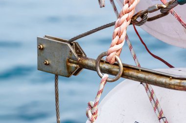 Yelken teknenin arka tarafında çelik halat ve paslı kanca. Arka planda Yunanistan ve tarihi kale bayrağı