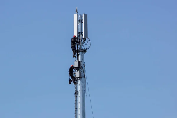 Mann, der auf einem hohen Turm oder Mast der Telekommunikation arbeitet. Arbeiten mit hohem Risiko. Wartung am Turm. — Stockfoto