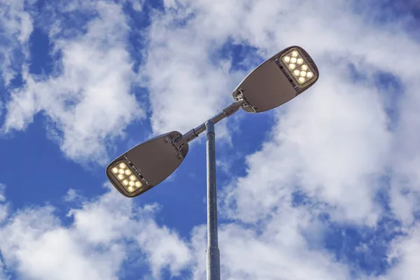 Three LED Street Lamps Affixed to an Iron Post Against a Deep Blue Sky Royalty Free Stock Images