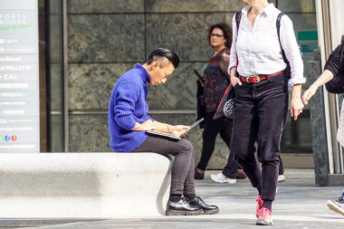 Milan, İtalya 4 Mayıs 2019: Kentin meydanındaki bankta otururken bilgisayar kullanan genç adam .