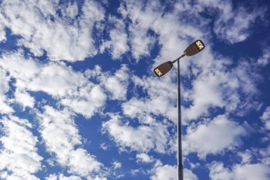 Üç LED sokak lambaları derin bir mavi gökyüzüne karşı demir bir yazı yapıştırılmış