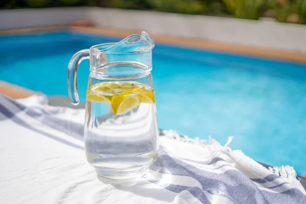 Frasco Vidro Com Água Limão Com Uma Piscina Fundo — Fotografia de Stock