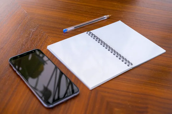 Üres Jegyzetfüzet Egy Tollal Egy Telefonnal Asztalon — Stock Fotó