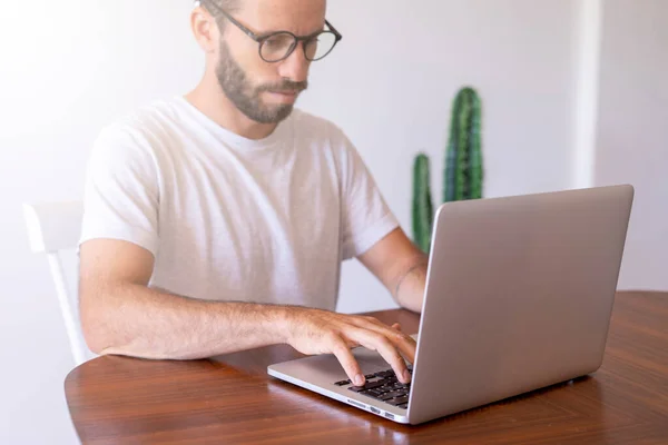 Young man with screen glasses typing on the computer