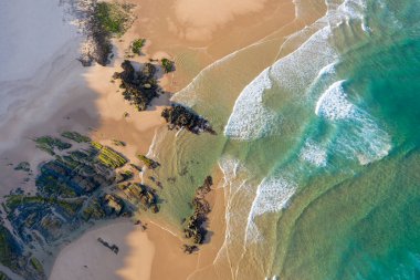 Yukarıdan kayalıklı boş bir sahilin manzarası. Deniz kenarında tatil turizmi. Sahilde tatiller