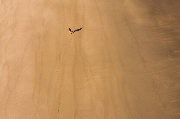 View of a person walking on a desert beach from above