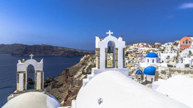 Oia Santorini Adası üzerinde sokaklarında Yunan Ortodoks Kilisesi'nin küçük çan kulesi sağda yukarıda Ege Denizi sularının derin bir uçurumun kenarında duruyor.