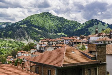 Beyaz tüylü bulutların üzerinde kırmızı kiremitli çatıya bir küçük Yunan dağ köyü.