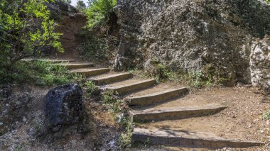 Eski merdiven harap ahşap adımları ağaçlar kalın dalları altında antik taş duvar geçmiş Rum Ortodoks Manastırı olduğu dağ tepesine kurşun.