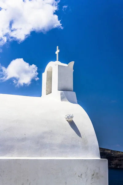 A small white bell tower in the Greek Orthodox Church on the street in a small mountain village.