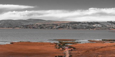 Yükselen güneşin ilk ışınları alp Titikaka Gölü kıyısında boyalı. Hangi gece boyunca kıyı ot ve çalılar üzerinde yavaş yavaş yatıyordu frost, erimeye başlar.