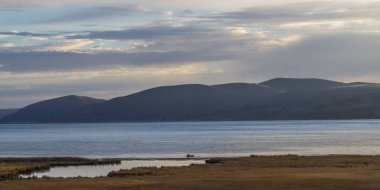 Yükselen güneşin ilk ışınları alp Titikaka Gölü kıyısında boyalı. Hangi gece boyunca kıyı ot ve çalılar üzerinde yavaş yavaş yatıyordu frost, erimeye başlar.