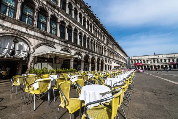 Early in the morning on St. mark\'s square in Venice, almost no tourists. On an empty square you can see rows of empty chairs and tables, and even janitors cleaning up the garbage left from the night.