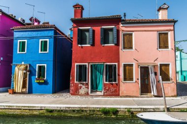 Eski renkli evler ve dar, sessiz kanal ile Burano adasında gün batımı.