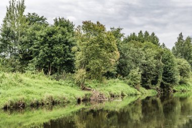 Fırtına bulutları Moskova yakınlarındaki sakin bir nehre yansıyor, yeşil çayırlar boyunca akıyor..
