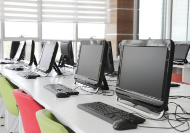 Bir okul bilgisayar laboratuvarında öğrenciler ve öğrenciler için monitörler ve klavyeli boş bilgisayar odası