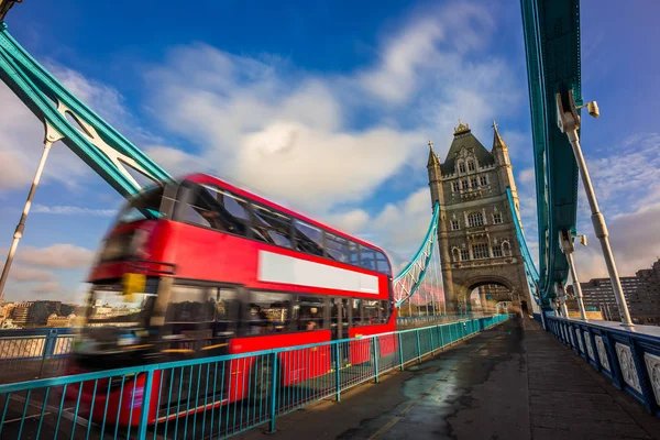 ロンドン イギリス 背景で銀行地区の高層ビルで有名なタワー ブリッジの動きの象徴的な赤い二階建てバス 青い空と雲 — ストック写真