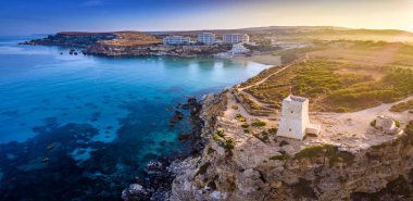 Ghajn Tuffieha, Malta - havadan panoramik görünümü Saat Kulesi, Golden Bay beach ve gündoğumu, berrak deniz suyu ile Ghajn Tuffieha sahil
