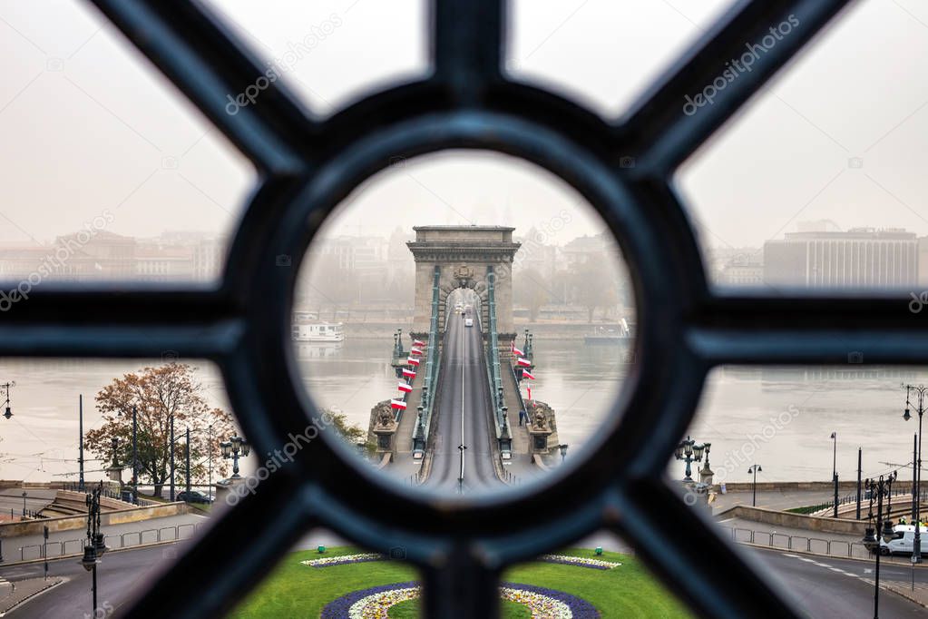 Budapest, Hungary - Szechenyi Chain Bridge looking through old iron railings at Clark Adam Square on a foggy autumn morning