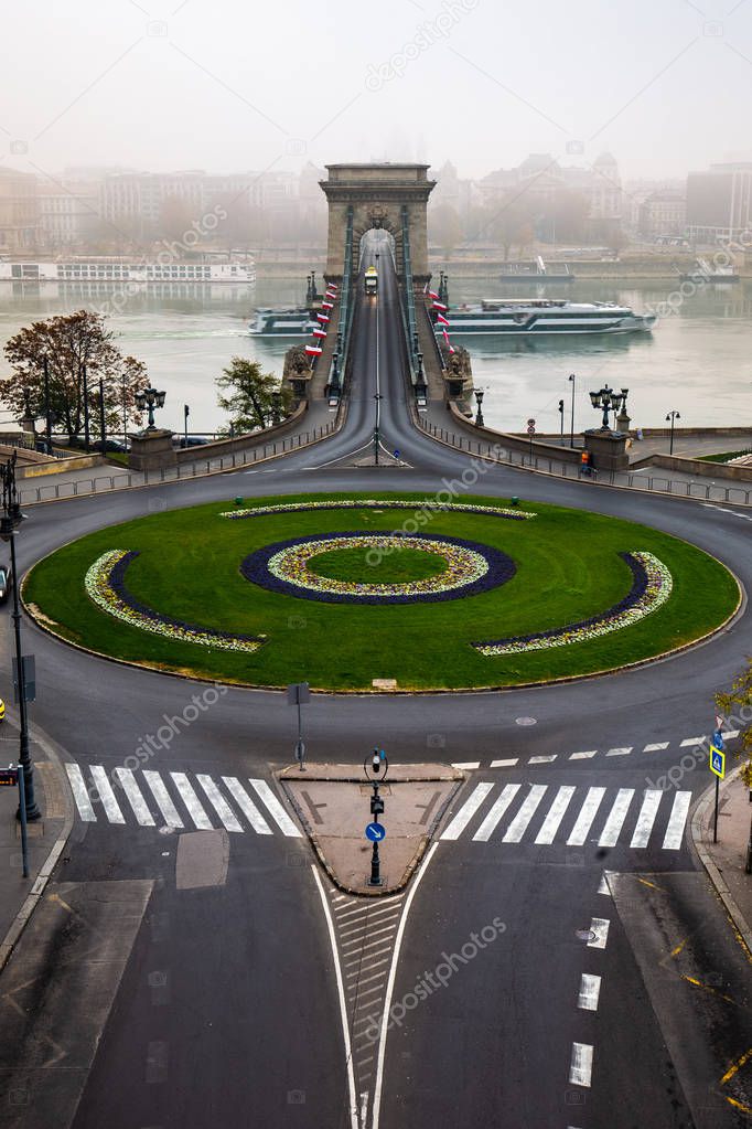 Budapest, Hungary - Clark Adam Square and Szechenyi Chain Bridge with cruise ship on River Danube on a foggy autumn morning