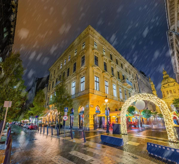 Budapest, Hungary - Snowy evening and Christmas market gate at the Zrinyi and Oktober 6 street corner with St.Stephen\'s Basilica at background