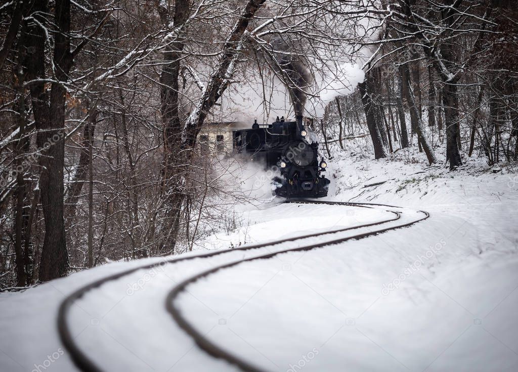 Budapest, Hungary - Beautiful winter forest scene with snow and old steam locomotive on the track in the Hungarian woods of Huvosvolgy