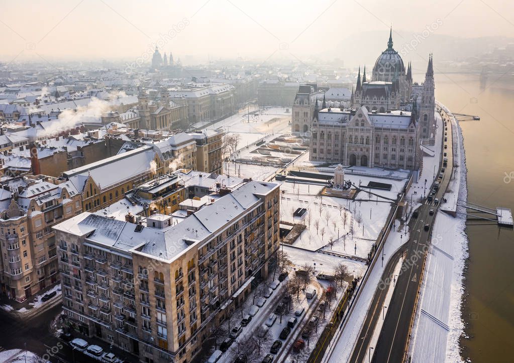 Budapest, Hungary - Aerial view of the snowy riverside of Pest with Parliament of Hungary and St.Stephen's Basilica on a misty winter morning