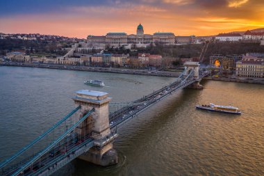 Budapeşte, Macaristan - Tuna Nehri üzerinde güzel bir altın gün batımı ve gezi tekneleri ile Szechanyi Zincir Köprüsü ve Buda Kalesi Kraliyet Sarayı havadan görünümü