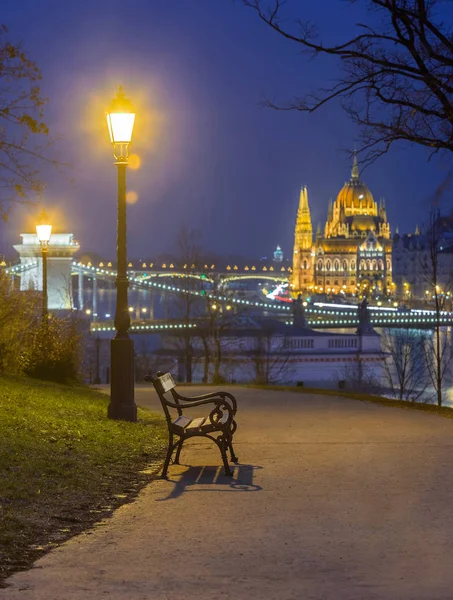 Budapest, Ungheria Panca e lampione in un parco nel distretto di Buda con il Parlamento ungherese adn Szechenyi Ponte delle Catene sullo sfondo durante l'inverno — Foto Stock