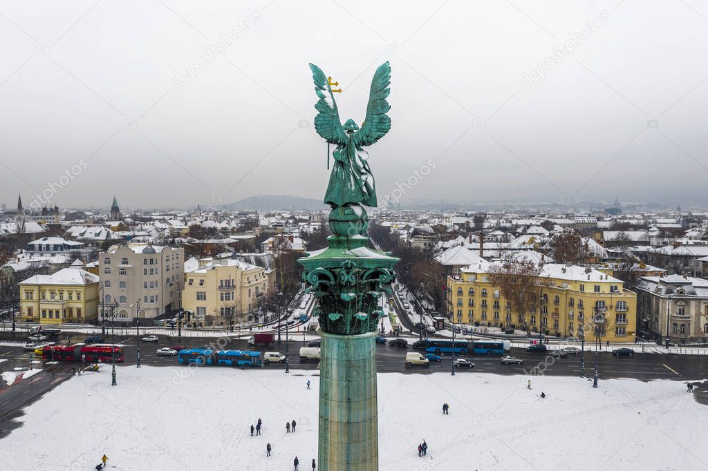 Budapest, Hungary - Aerial view of the snowy Heroes' Square with angel sculpture, busses and Andrassy street on a winter morning