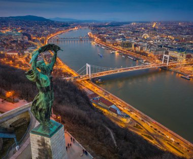 Budapeşte, Macaristan - Yukarıdan Budapeşte 'nin havadan panoramik manzarası, Özgürlük Heykeli, Elisabeth ve Szecheni Zincir Köprüsü ve Tuna Nehri üzerinde mavi saatte gezici bir tekne