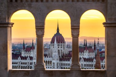 Budapest, Hungary - The Hungarian Parliament building at sunrise looking through old stone windows clipart