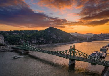 Budapeşte, Macaristan - Tuna Nehri ve Gellert Tepesi üzerinde güzel bir günbatımı manzaralı gökyüzü manzaralı gezi teknesi, Özgürlük Köprüsü, Buda Şatosu ve arka planda Özgürlük Heykeli