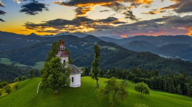 Skofja Loka, Slovenya - Güzel Sveti Tomaz (Saint Thomas) tepedeki kilisede yaz mevsiminde arka planda Julian Alps ile inanılmaz renkli gün batımı