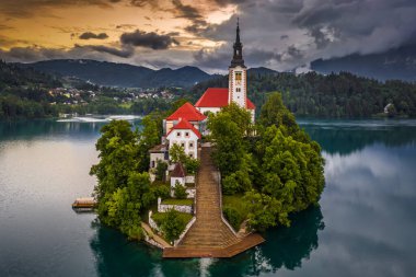 Bled, Slovenya - Maria 'nın Bled Gölü' ndeki (Blejsko Jezero) küçük bir adada yaz mevsiminde dramatik bir altın gün batımıyla birlikte güzel bir hac kilisesi manzarası