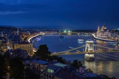 Budapeşte, Macaristan - Macaristan Szechenyi Zinciri Köprüsü 'nü Macaristan Parlamentosu ile bir gece fotoğrafı, Tuna Nehri üzerinde gemiler ve gün batımından sonra açık mavi gökyüzü