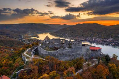 Visegrad, Macaristan - Sonbahar yaprakları ve ağaçlarıyla güzel yüksek Visegrad şatosunun insansız hava aracı görüntüsü. Dunakanyar ve arka planda altın gün batımı