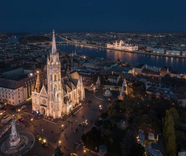 Budapeşte, Macaristan - Balıkçı Kalesi (Halaszbastya), Margaret Köprüsü ve Macaristan Parlamentosu ile mavi saatte aydınlatılmış güzel Matthias Kilisesi 'nin insansız hava aracı görüntüsü