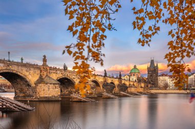 Prag, Çek Cumhuriyeti - Çek bayrağı, sıcak gün batımı ışıkları ve sonbahar yeşillikleriyle ünlü Charles Köprüsü (Karluv most) ve Assisi Kilisesi 'nden Aziz Francis' in uzun pozlu görüntüleri