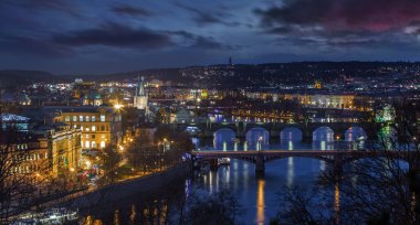 Prag, Çek Cumhuriyeti - Prag şehrinin panoramik silueti gece mor bulutlarla kaplandı. Bunlar arasında ünlü Charles Köprüsü, Assisi Kilisesi 'nin Aziz Francis Köprüsü ve Vltava Nehri yer almaktadır.