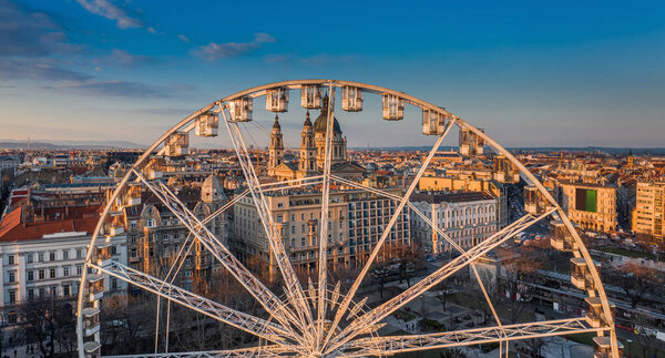 Budapest, Hungary - Aerial panoramic view of the ferris wheel at Elisabeth Square (Erzsebet ter) at sunset with St. Stephen's Basilica and blue sky at background