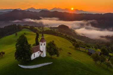 Skofja Loka, Slovenya - Sveti Tomaz 'ın (Aziz Thomas) güzel tepelik kilisesinin havadan panoramik manzarası ve yaz mevsiminde inanılmaz sisli gündoğumu ve Julian Alpleri