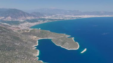 4K plaj manzaralı, mavi su ve Akdeniz kıyı şeridi boyunca uzanan yol.