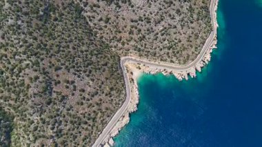 Sahilde, yolda, mavi gökyüzünde ve turkuaz denizde 4K drone görüntüsü.